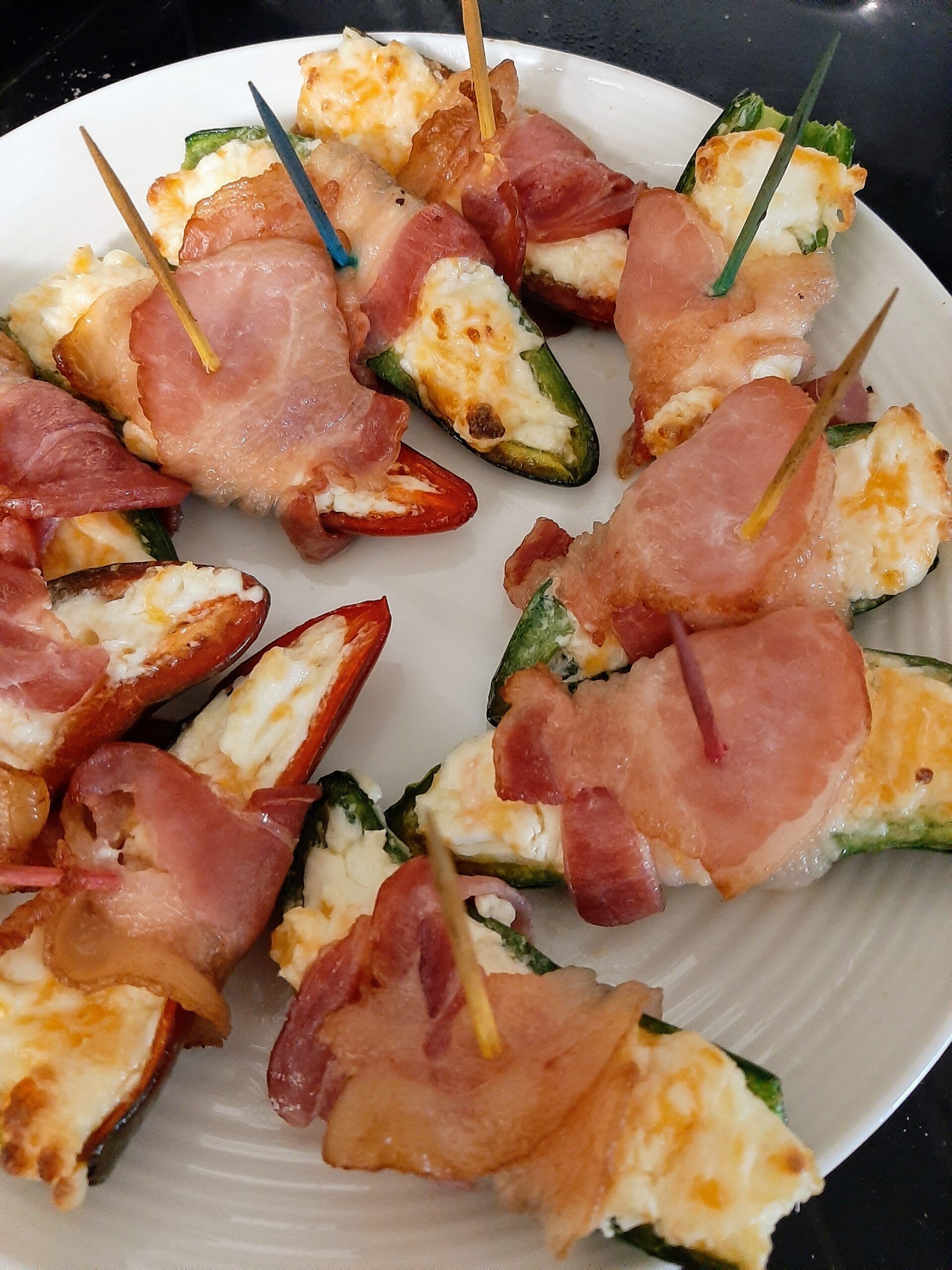 bacon wrapped jalapeno poppers arranged on a white plate